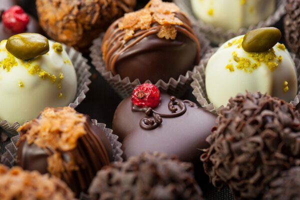 Los dulces de chocolate negro están decorados con bayas y pistachos