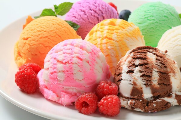 Boules de crème glacée colorées sur une assiette de framboises