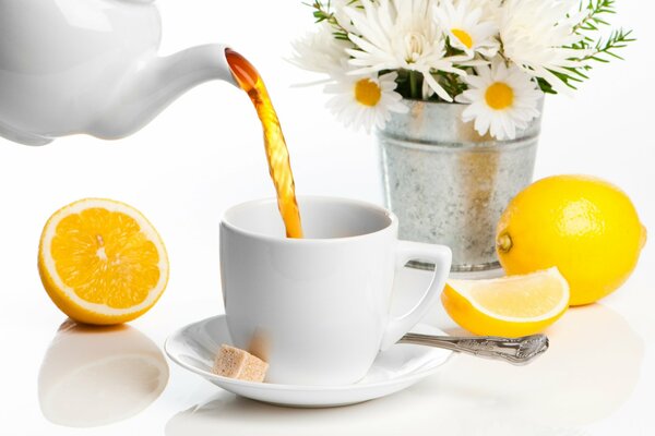 Tea with lemon on the background of a bucket with daisies