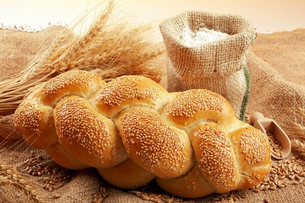 A bag of flour next to bread and wheat