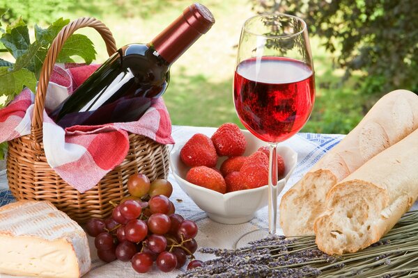 Багет, клубника, виноград, бокал красного вина на природе
