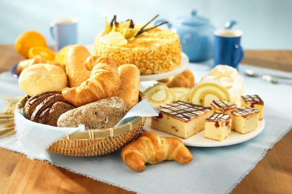 Fresh croissants, cake and lemons with tea