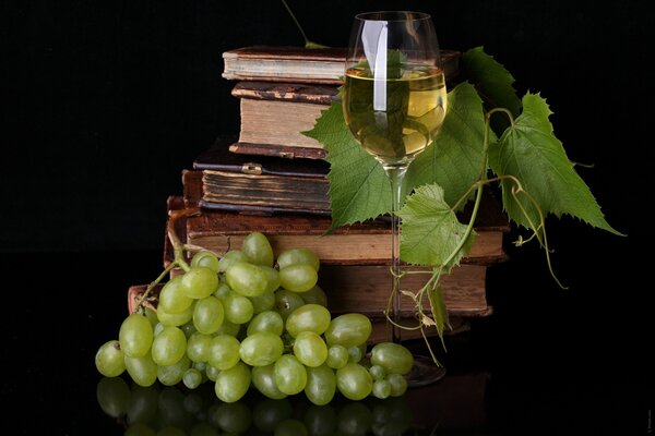 Una Copa de vino de uva blanca y una pila de libros