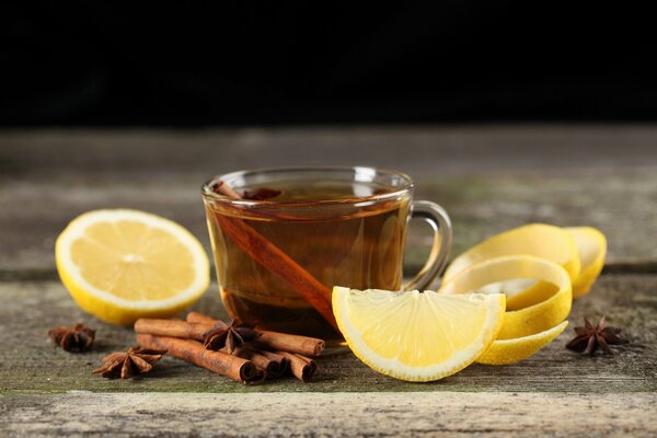 A cup of tea, lemon slices and cinnamon sticks