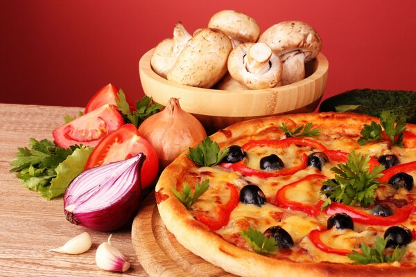 Halves of onions, tomatoes and a wooden bowl with champignons near the pizza stand