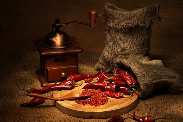 On a tray, red chili pepper, scattered from the bag, whole and already ground next to it