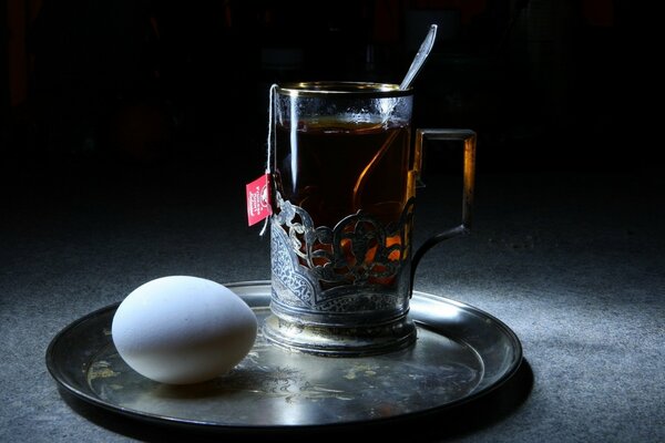 Becher mit Tee und Ei auf einem Tablett