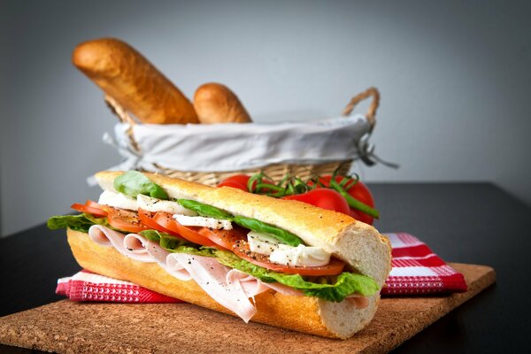 In einem Brotkorb, neben einem Hot Dog mit Tomaten, Schinken und Käse