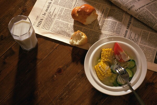 Merienda ensalada, leche y periódico cerca