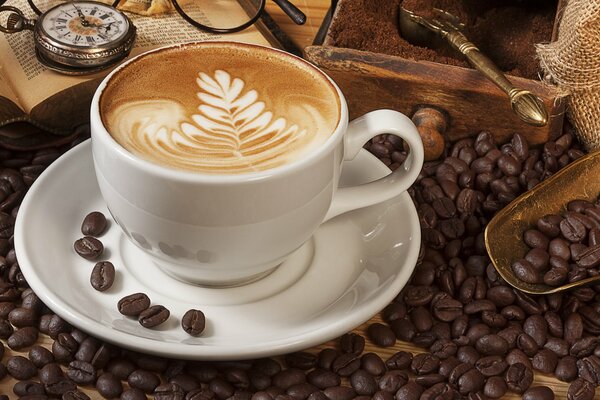 Cappuccino auf dem Hintergrund von Büchern und Kaffeebohnen