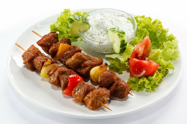 Barbecue with vegetables, herbs and sauce on a white plate