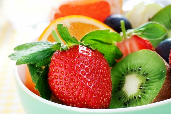 Kiwi, strawberry and orange placed in a bowl