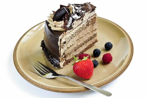 Tranche de gâteau avec glaçage au chocolat et crème à côté des baies, couché sur une soucoupe
