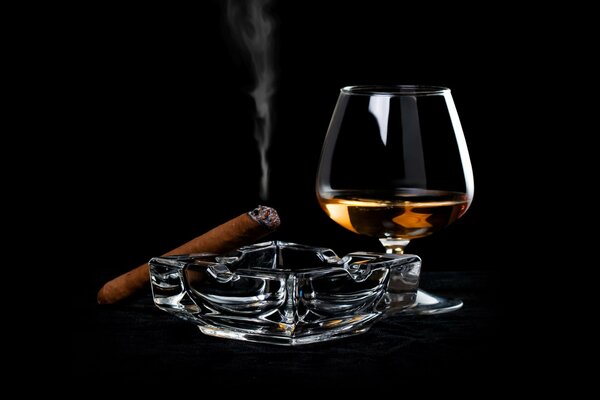 Un bicchiere di liquore e un sigaro inalterato