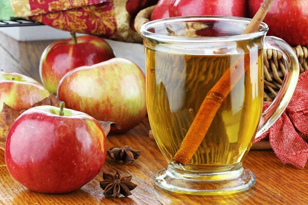 Apfelsaft in einem Glas mit einem Strohhalm auf einem Tisch mit Äpfeln