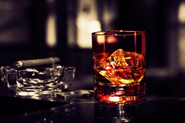 Sul tavolo un bicchiere di whisky con ghiaccio