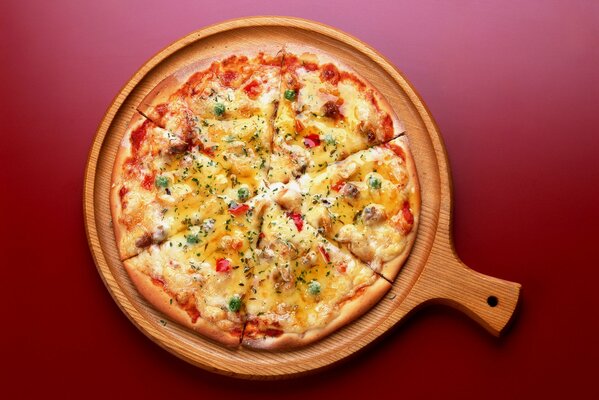 Leckere Pizza auf einem Holztablett , auf einem roten Tisch