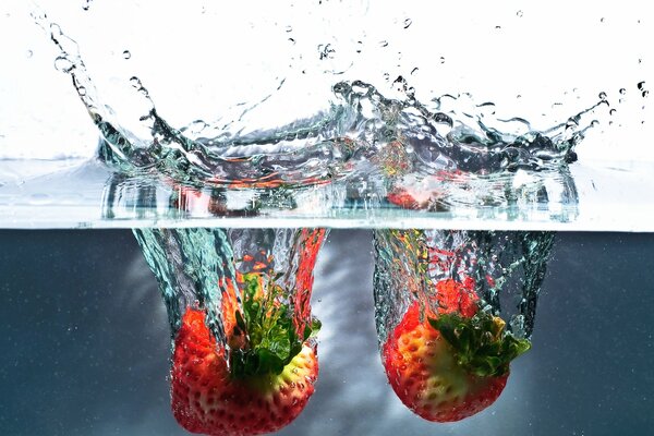Ripe strawberries falling into the water