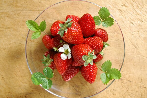 A plate of juicy strawberries with green leaves