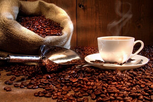 Coffee beans scattered on the table with a cup of coffee