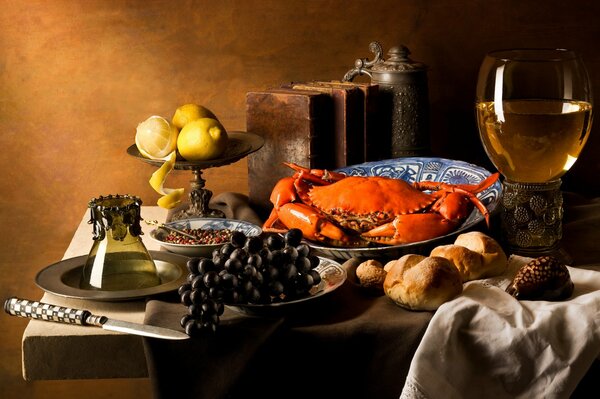 Cangrejo en un plato sobre la mesa con uvas, limones y una bebida