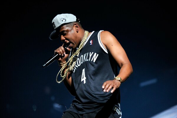 Jay-z in a black T-shirt and chains with a microphone in his hands