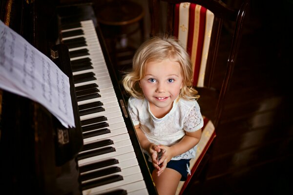 A little girl is sitting at the piano