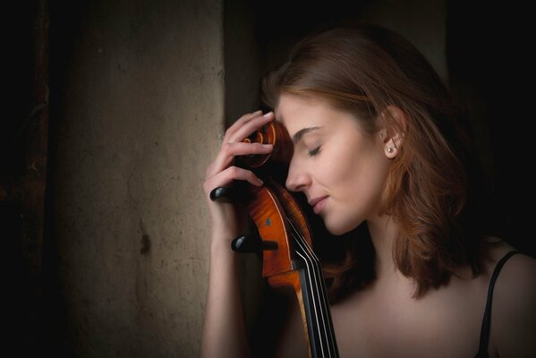 Joven se apoya en un violonchelo