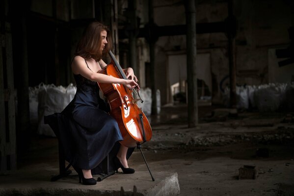 Chica en vestido negro se sienta con un violonchelo