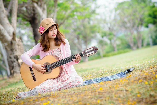 La ragazza con il cappello suona la chitarra