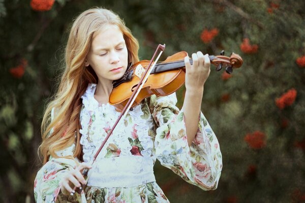 A girl in a floral dress plays the violin