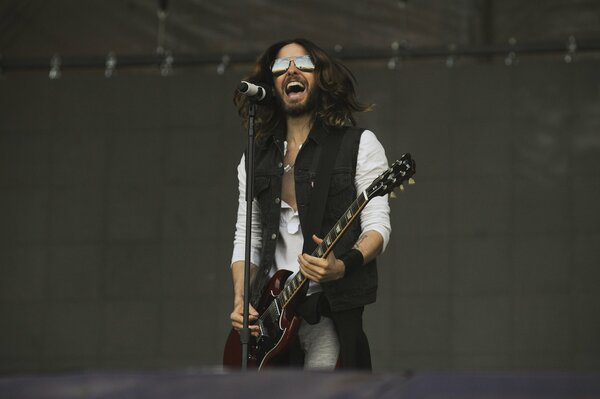 A singer with glasses plays the guitar and sings