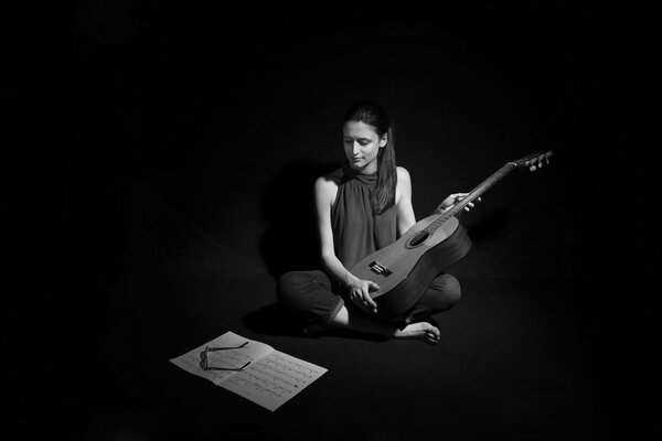 A girl learns sheet music with a guitar