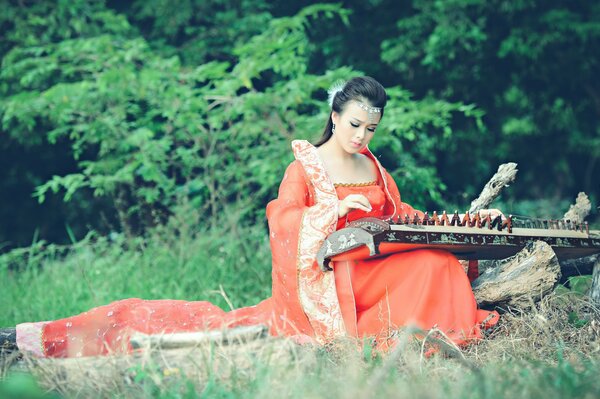 Chica tocando un instrumento musical asiático