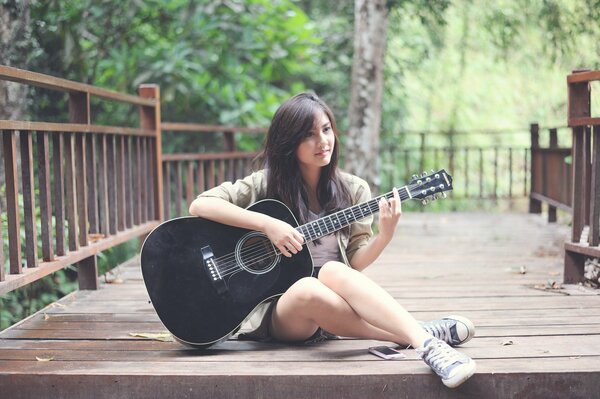 Fille avec une guitare assis sur un pont