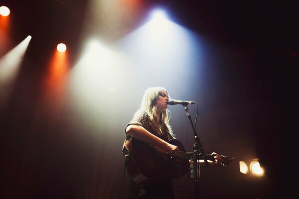 A musician with a guitar in the spotlight