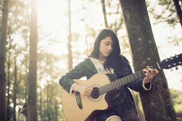 Fille jouant de la guitare dans les bois