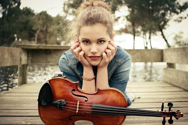 Fille avec violon à l automne sur la jetée