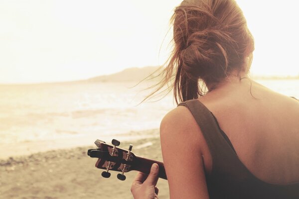 Dziewczyna gra na gitarze nad jeziorem