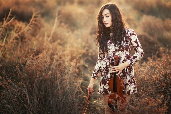 A girl with a violin in her hand in a field