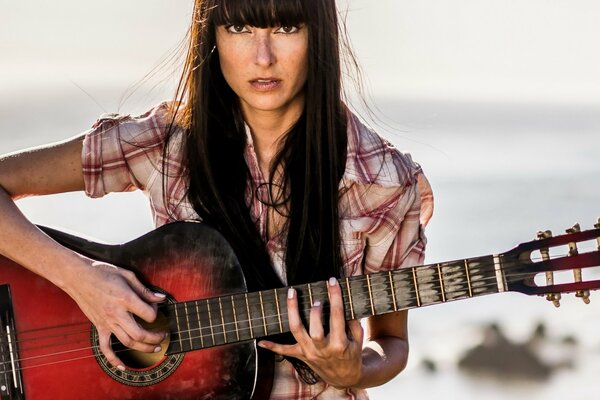 Chica con guitarra en la orilla