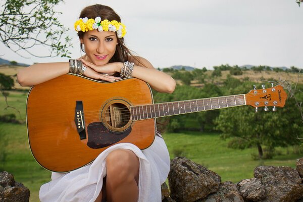 Beautiful girl in a wreath with a guitar