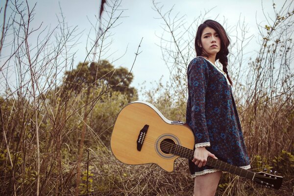 Ragazza con chitarra sullo sfondo della natura