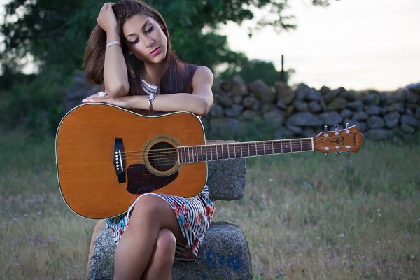 Belle fille dans un champ avec une guitare