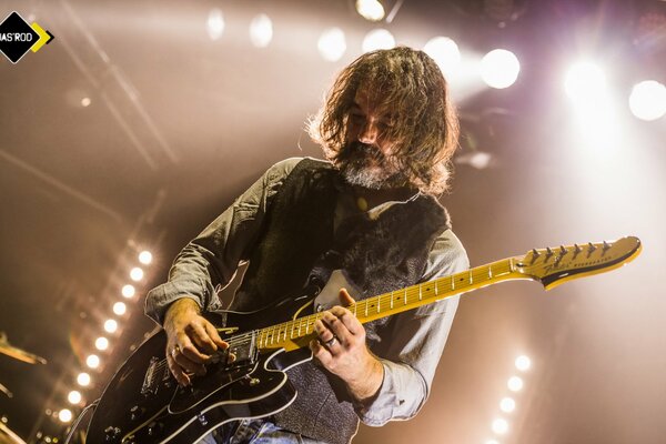 Fotografía de un guitarrista barbudo a la luz de los sofitos