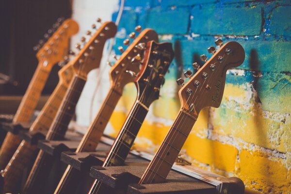 Guitar fingerboards on a blue-yellow brick wall background