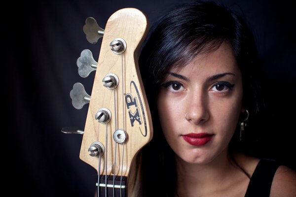 The face of a girl with a guitar neck on a black background