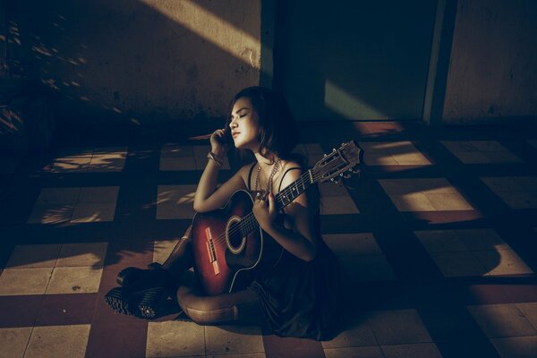 Ragazza con la chitarra seduta sul pavimento