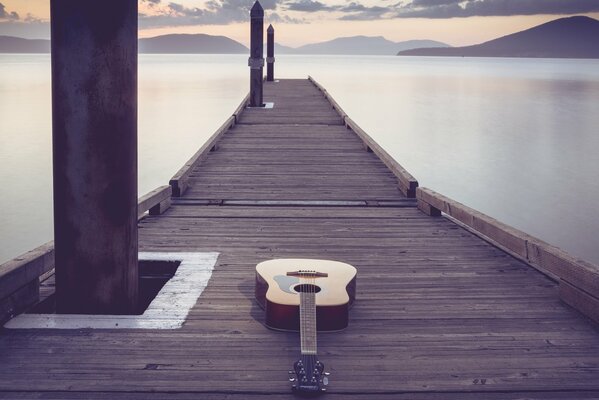 Gitara leży na długim drewnianym moście