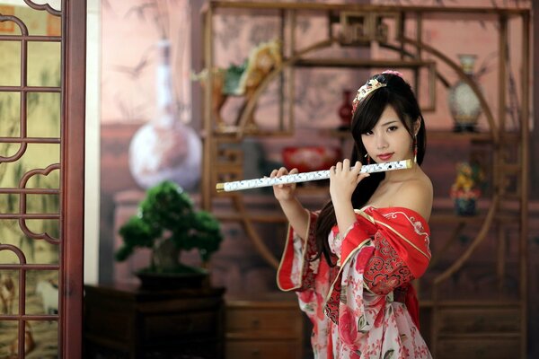 Asian girl in red dress plays flute